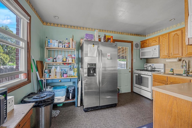 kitchen featuring white appliances, plenty of natural light, a sink, and light countertops