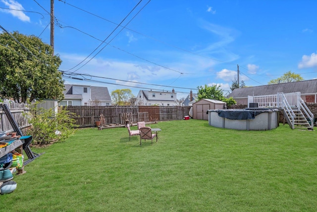 view of yard featuring an outdoor structure, a fenced in pool, a fenced backyard, and a storage unit