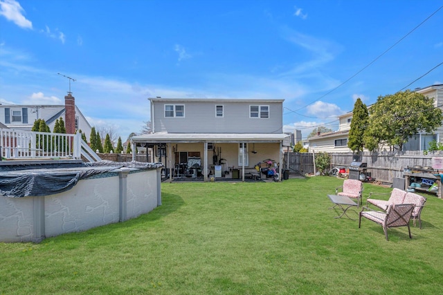 rear view of property featuring a fenced in pool, a fenced backyard, a patio area, and a yard