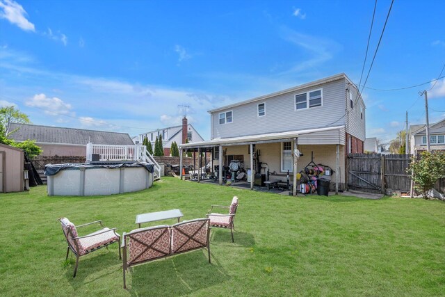 rear view of house with brick siding, a fenced in pool, a fenced backyard, a yard, and a patio