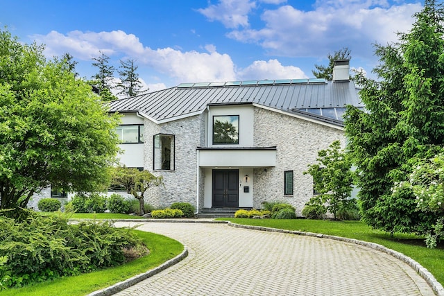 view of front of home with stone siding, metal roof, and a standing seam roof