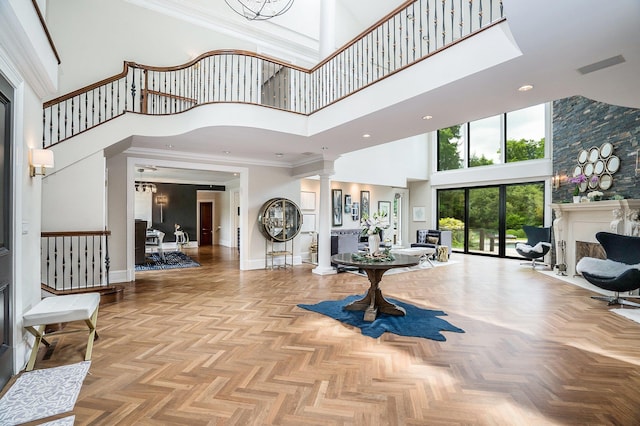 foyer with baseboards, ornate columns, crown molding, and a towering ceiling