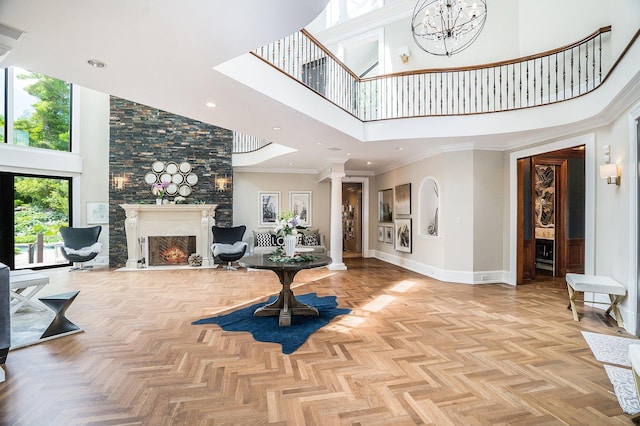 foyer featuring a lit fireplace, decorative columns, baseboards, a towering ceiling, and recessed lighting