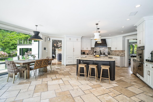 kitchen with tasteful backsplash, stone tile floors, stainless steel double oven, and a kitchen island
