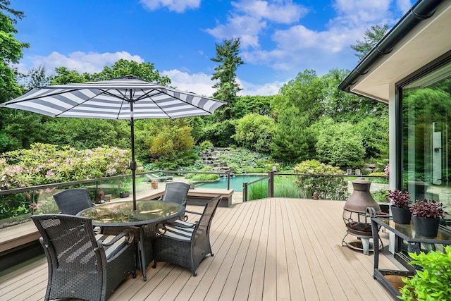 wooden deck featuring a water view, outdoor dining area, and an outdoor pool