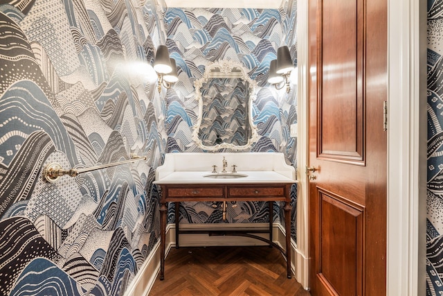bathroom featuring baseboards, vanity, and wallpapered walls