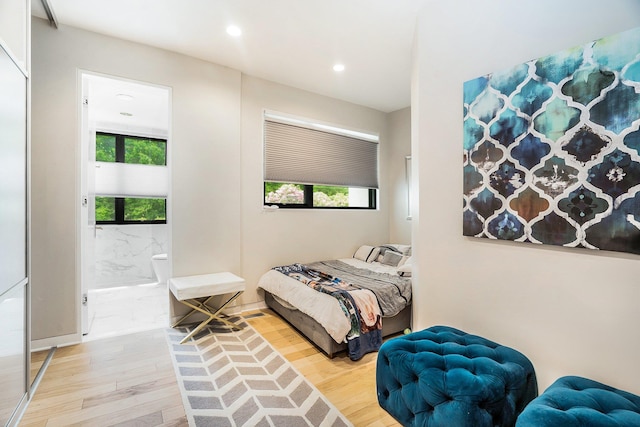 bedroom with multiple windows, light wood-style floors, connected bathroom, and recessed lighting
