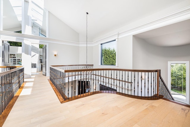 hallway featuring wood finished floors, an upstairs landing, and high vaulted ceiling