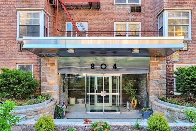 view of exterior entry featuring a balcony and brick siding