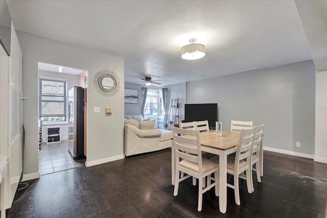 dining space featuring baseboards, ceiling fan, and dark wood-style floors
