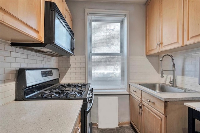 kitchen featuring light brown cabinets, gas range, light countertops, tasteful backsplash, and a sink