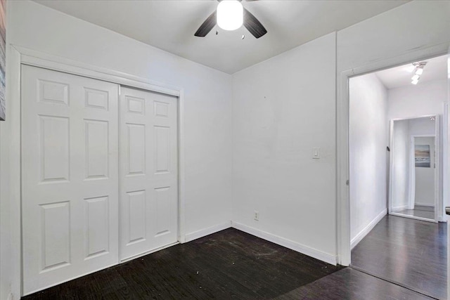unfurnished bedroom with baseboards, dark wood finished floors, ceiling fan, and a closet