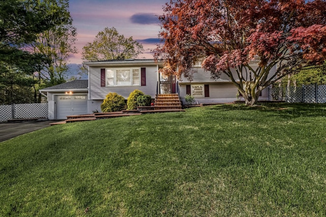 split level home with aphalt driveway, a front lawn, and a garage