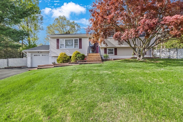 tri-level home with fence, a garage, aphalt driveway, and a front lawn