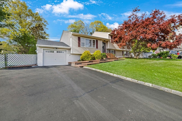 split level home featuring an attached garage, driveway, and a front lawn