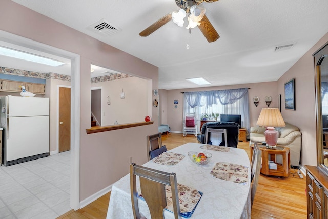 dining area with visible vents, baseboards, ceiling fan, and a skylight