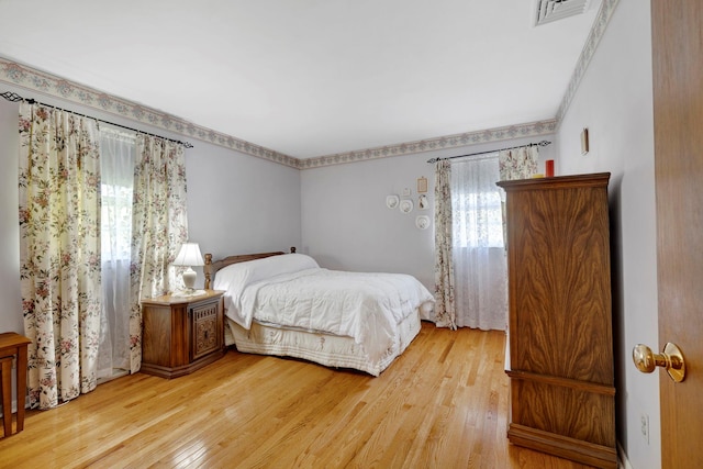 bedroom with visible vents, ornamental molding, and light wood-style floors