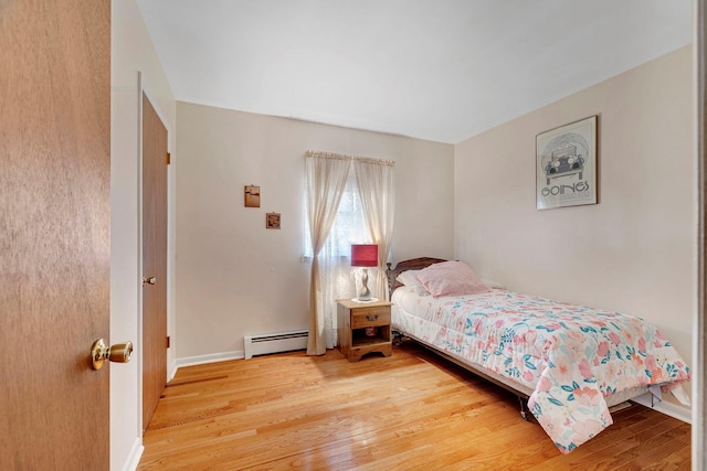 bedroom featuring baseboards, a baseboard heating unit, and light wood-style flooring