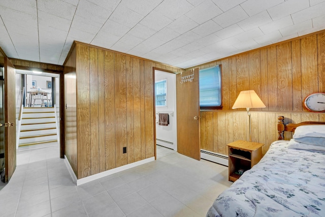 tiled bedroom featuring baseboards, wood walls, and a baseboard radiator