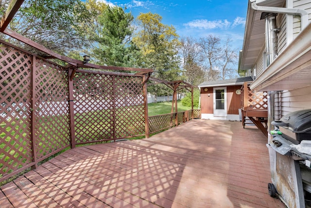 wooden terrace featuring a lawn and a grill