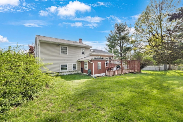 back of house featuring fence, a yard, a chimney, and a deck