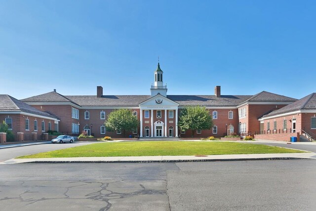 view of front facade with a chimney and a front lawn