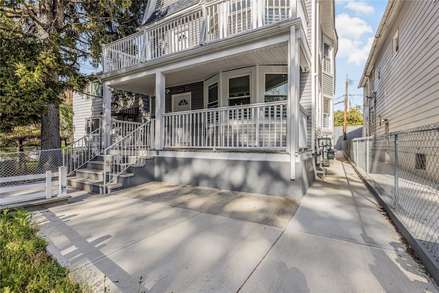 view of front of home with fence, a balcony, and covered porch