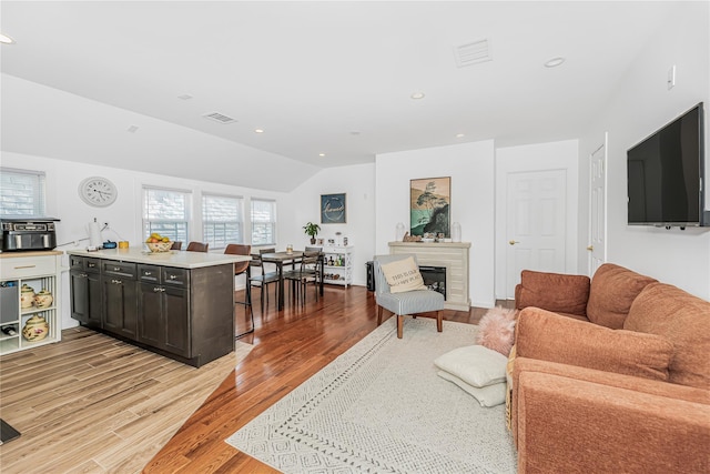 living area with recessed lighting, visible vents, light wood-style flooring, and vaulted ceiling