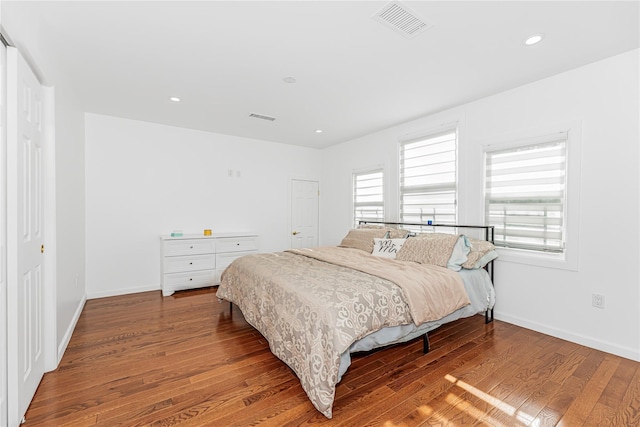 bedroom with baseboards, visible vents, and wood finished floors
