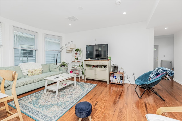 living room with recessed lighting, visible vents, and wood finished floors