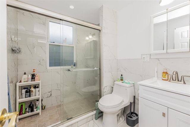 full bath with toilet, tile walls, a shower stall, and vanity
