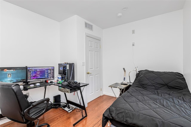 bedroom with baseboards, wood finished floors, and visible vents