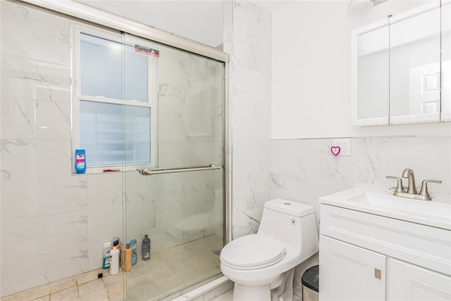 bathroom with toilet, tile walls, a marble finish shower, and vanity