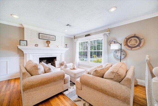 living area featuring a textured ceiling, wood finished floors, visible vents, and crown molding