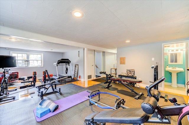 exercise room with baseboards, a sink, and recessed lighting