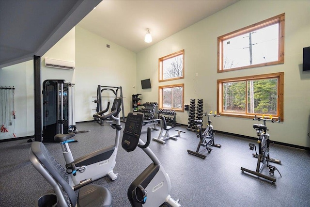 exercise room featuring baseboards, a high ceiling, and a wall unit AC
