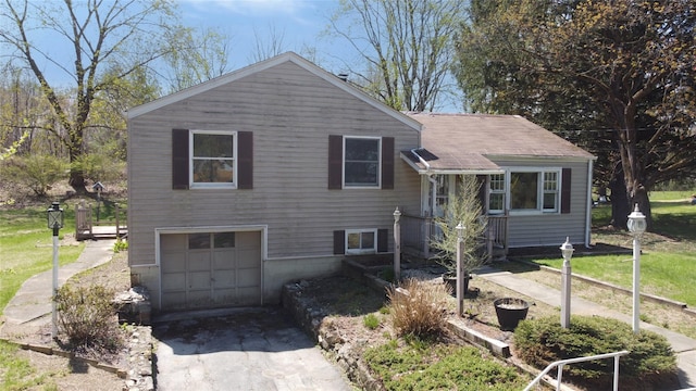 tri-level home with concrete driveway, a shingled roof, and an attached garage