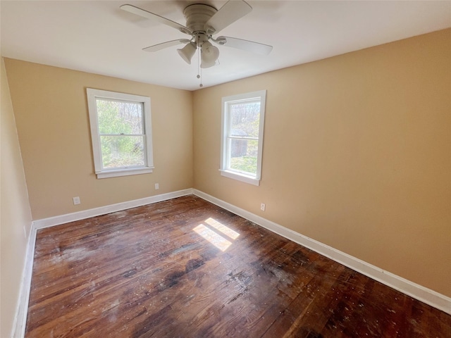 spare room featuring dark wood-style flooring, ceiling fan, and baseboards