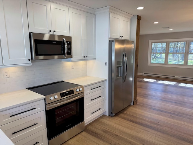 79 Enfield Ct Unit B, Ridge, NY 11961 - kitchen with light wood-type flooring, stainless steel appliances, a baseboard radiator, and tasteful backsplash