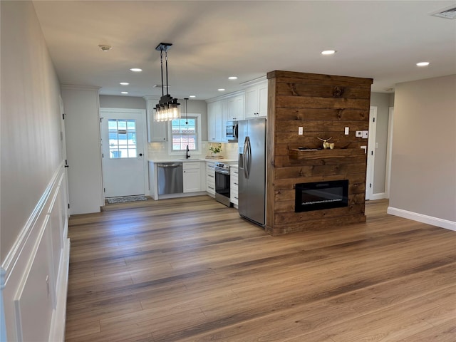 79 Enfield Ct Unit B, Ridge, NY 11961 - kitchen featuring light countertops, visible vents, appliances with stainless steel finishes, a large fireplace, and white cabinetry