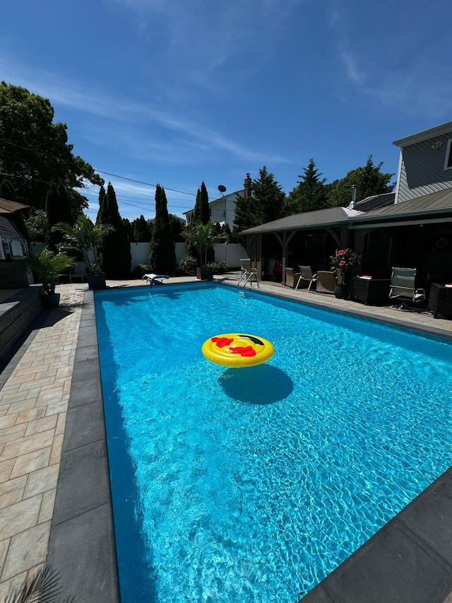 pool with a diving board, fence, and a patio area