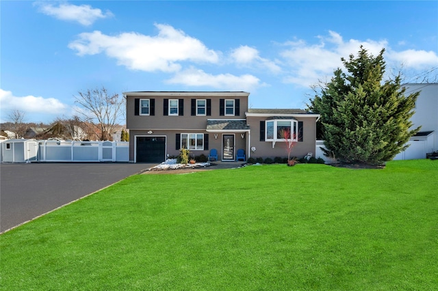 tri-level home with fence, an attached garage, a front lawn, aphalt driveway, and a storage shed