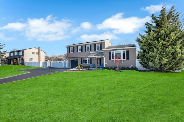 view of front of property with fence, an attached garage, a front yard, and aphalt driveway