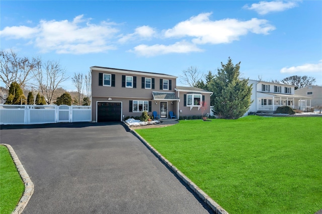 tri-level home with a garage, fence, a front yard, and aphalt driveway