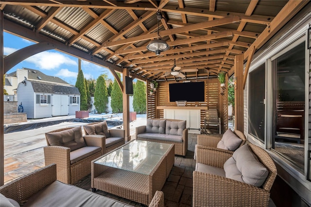 view of patio / terrace featuring ceiling fan, outdoor dry bar, an outdoor living space, a storage shed, and an outbuilding