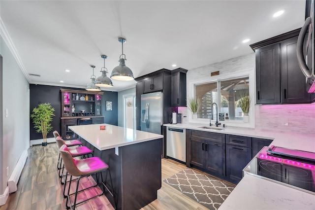 kitchen featuring a center island, a sink, a baseboard radiator, stainless steel appliances, and recessed lighting