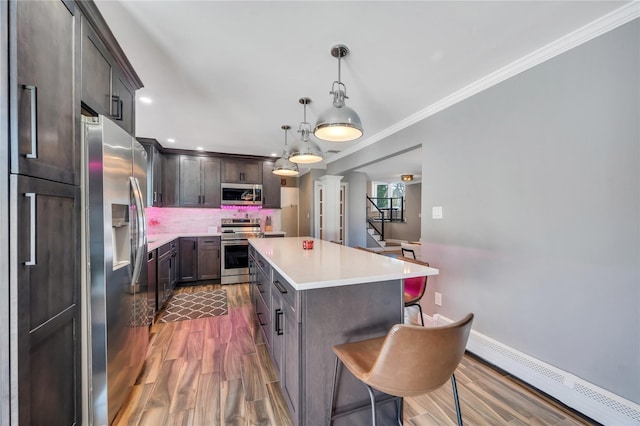 kitchen featuring ornamental molding, a kitchen bar, a center island, dark wood finished floors, and appliances with stainless steel finishes