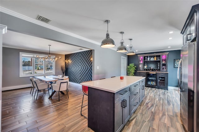 kitchen featuring visible vents, freestanding refrigerator, wine cooler, baseboards, and a kitchen breakfast bar