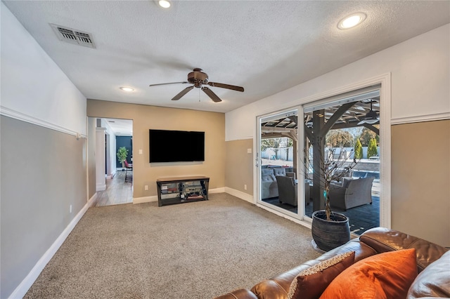 living area with visible vents, baseboards, a textured ceiling, a ceiling fan, and carpet