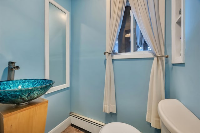 half bathroom featuring vanity, toilet, baseboards, and a baseboard radiator
